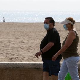 Dos personas protegidas con mascarilla pasean por la playa en València. /Europa Press