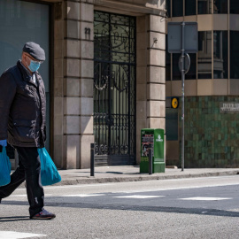 Un home que porta borses de la compra camina en la deserta Via Laietana causa de les mesures de confinament. Foto: Paco Freire/SOPA/ DPA/ Europa Press