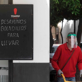 Un trabajador protegido con una máscara reparte en un bar de Córdoba. EFE/Rafa Alcaide/Archivo