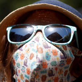 Una niña con mascarilla y con sombrero para protegerse del calor camina por Madrid este martes. | EFE