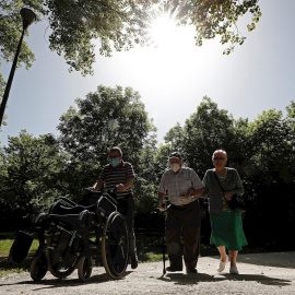 Dos personas mayores acompañados de un familiar caminan por el paseo del Arga, en la localidad navarra de Huarte. /EFE