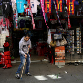 El empleado de una tienda de objetos turísticos del centro de Madrid barre la acera. REUTERS/Susana Vera