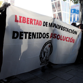 Jóvenes integrantes del Movimiento Antirrepresivo de Madrid con una pancarta en la que se lee, `Libertad de Manifestación, Detenidos Absolución´, concentrados frente a los juzgados de Plaza de Castilla en apoyo a los detenidos en el centro de Madrid d