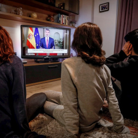 Tres jóvenes ven el discurso extraordinario del rey Felipe VI, en un mensaje por televisión dirigido a los españoles en relación con la crisis del coronavirus. EFE/José Manuel Vidal