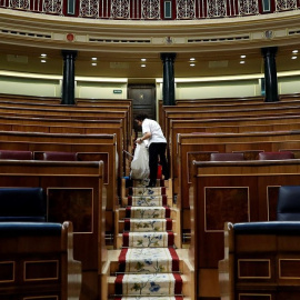Una empleada de la Cámara limpia el hemiciclo del Congreso vacío