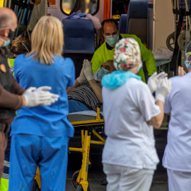 Un paciente que baja de una ambulancia participa en el apluaso al personal sanitario y de seguridad del hospital Virgen de la Salud de Toledo este domingo. Los sanitarios han agradecido el apoyo de los ciudadanos que se han acercado convocados a través d