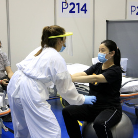 Una pacient que va tenir un edema cerebral difús com a seqüela de la Covid-19 fa rehabilitació amb una fisioterapeuta; al costat, el seu acompanyant, al Pavelló Salut Vall d'Hebron. ACN/ Laura Fíguls