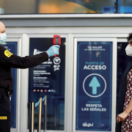 19/05/2020.-  Una persona de seguridad  toma la temperatura corporal a una mujer en un centro comercial. / EFE - CHEMA MOYA