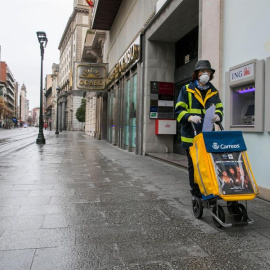 Una trabajadora del servicio de Correos realiza su trabajo por las calles casi desiertas de Zaragoza el pasado lunes. EFE/Javier Cebollada