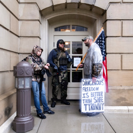 Manifestantes contra las medidas de confinamiento decretadas por el gobernador de Michigan, Gretchen Whitmer, se refugian de la lluvia en una de las entradas del Capitolio del Estado, en la localidad de Lansing. REUTERS/Seth Herald