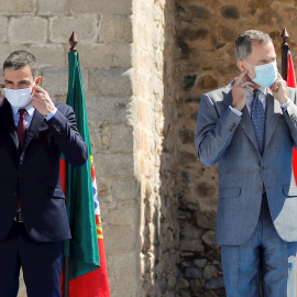 01/07/2020.- El presidente del Gobierno, Pedro Sánchez (i) y el rey Felipe VI (d) se ponen las mascarillas antes de la foto oficial en la explana del castillo de Elvas durante el acto oficial de la reapertura, tras tres meses y medio cerradas por el coro