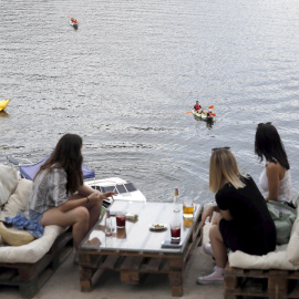 Varias personas disfrutan del aperitivo en el chiringuito La Martuka, hoy domingo en el madrileño pantano de San Juan, en un día soleado y con altas temperaturas. EFE/J.J. Guillén