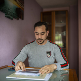 Eresto Vigoa, víctima de una estafa inmobiliaria, revisa sus denuncias en el salón de la casa de un amigo que le acoge en el barrio madrileño de San Blas.- J.V.