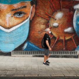 01/07/2020.- Un hombre camina junto a un mural en homenaje a los sanitarios que han estado en primera línea en la batalla contra el coronavirus en una calle de Melide en A Coruña. EFE/ Eliseo Trigo