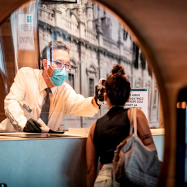 Un recepcionista de hotel toma la temperatura a una huesped por la pandemia de coronavirus. EFE/ José Manuel Vidal/Archivo