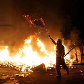 Un manifestante sostiene una bandera estadounidense quemada durante una protesta por George Floyd, en St. Louis, Missouri. REUTERS / Lawrence Bryant
