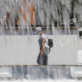 Una mujer pasa ante una fuente en Córdoba que este fin de semana registra altas temperaturas con aviso naranja decretado por la Agencia Estatal de Meteorología (Aemet). EFE/Salas