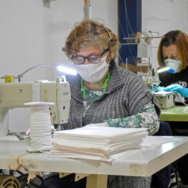 Varias mujeres fabrican mascarillas mientras colaboran de forma altruista con la empresa segoviana Mundo Laboral, que ha decidido parar la producción de su taller de confección para fabricar mascarillas | EFE