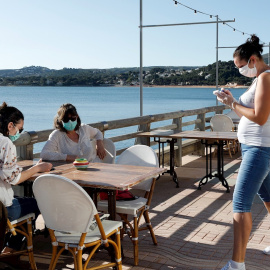 Una camarera atiende a dos clientas en una terraza en la localidad Alicantina de Denia, uno de los territorios de España que comienza la Fase 1.EFE/ Juan Carlos Cárdenas