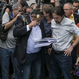 Julio Sanz,iz, presidente de la Federación Profesional del Taxi, recibe el impacto de un huevo en la cabeza mientras conversa con el líder de Podemos, Pablo Iglesias,c-d., en las proximidades de la plaza de Neptuno donde hoy el gremio de los taxistas ma