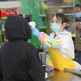 GRAF7492. MADRID, 29/04/2020.- Una trabajadora usa un termómetro de infrarrojos para tomar la temperatura a los clientes durante la reapertura del supermercado Asia, en el barrio madrileño de Usera este miércoles. EFE/Rodrigo Jiménez