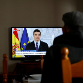 Un anciano ve en la televisión una rueda de prensa de Pedro Sánchez sobre el coronavirus. / JON NAZCA (REUTERS)