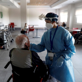 Una sanitaria atiende a un anciano alojado en una residencia en el barrio madrileño de Villaverde, mientras se procede a la desinfección de las instalaciones para evitar la propagación del coronavirus. EFE/Mariscal