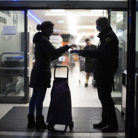 Un trabajador de un supermercado le da guantes a una clienta durante el estado de alarma por la emergecia del coronavirus. / JAIRO VARGAS