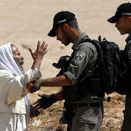 Un palestino discute con soldados israelíes mientras un buldócer destruye una granja y unas tierras de cultivo usadas para criar ovejas en la zona de Masafer, al sur de Hebrón (Palestina). (ABED AL HASHLAMOUN)