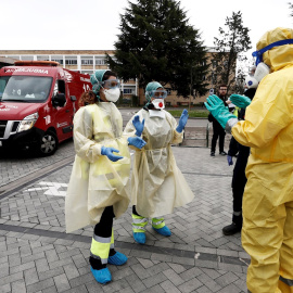 Dos enfermeras que acaban de trasladar en ambulancia a un enfermo que ha dado positivo en el test del COVID-19 solicitan ayuda de un efectivo de la DYA Navarra que en coordinación con el departamento de Salud ha implantado un túnel de desinfección en e