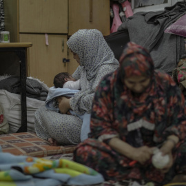 Dos mujeres palestinas pasan la noche en la escuela de la ONU en Khan Younis, al sur de Gaza. / Haitham Imad (EFE)