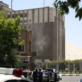 Fuerzas de seguridad permanecen en el exterior del edificio del Parlamento iraní, de donde se ver salir humo. | REUTERS