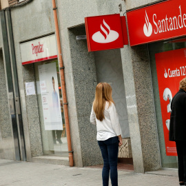 Un par de personas utilizan un cajero automático de una oficina del Banco Santander, en Barcelona, situada junto a una sucursal del Popular. REUTERS/Albert Gea