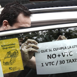 Un taxista pega en su taxi un cartel de protesta contra el incumplimiento de la proporción 1/30 entre licencias VTC y taxi. EFE