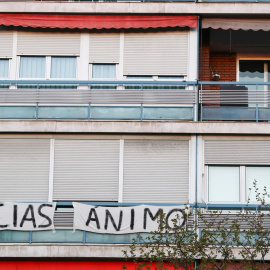 Una pareja se besa en el balcón junto a una pancarta de un vecino que reza "gracias" y "ánimo". Sergio Pérez/Reuters