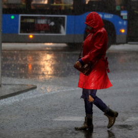 Una mujer camina por la calle durante la tormenta registrada esta mañana en Madrid. EFE/ Fernando Alvarado