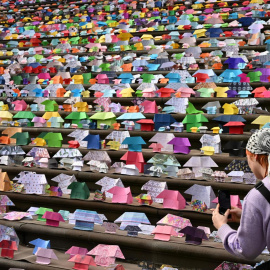 na persona toma una fotografía de las casas de origami colocadas en las escaleras del Parlamento estatal de Victoria en Melbourne, Australia, este miércoles, cono forma de revindicar acciones contra la escasez de viviendas sociales.- EFE/ James Ros