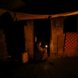 Mujer palestina sujeta una vela a la puerta de su casa durante un apagón en el Sur de la Franja de Gaza REUTERS/Ibraheem Abu Mustafa