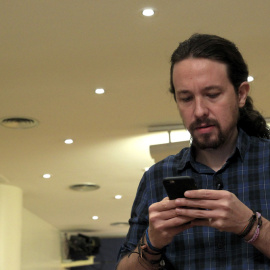 El secretario general de Podemos, Pablo Iglesias, mira su móvil poco antes de comparecer ante los medios de comunicación en el Congreso. EFE/Chema Moya