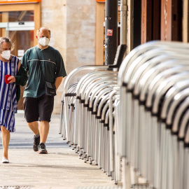 Un hombre y una mujer pasan ante la terraza recogida de un bar en el centro de Vitoria este miércoles, en el que se ha sabido que tres personas fallecieron la semana pasada en Euskadi con infección por coronavirus. EFE/ David Aguilar