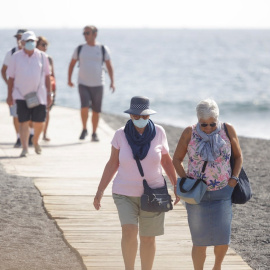 Varios turistas pasean este viernes por las inmediaciones del hotel en el que desde el pasado lunes permanecen incomunicados sus huéspedes y trabajadores al dar positivo en coronavirus cuatro de los que se alojaban en el centro turístico de Adeje, en el
