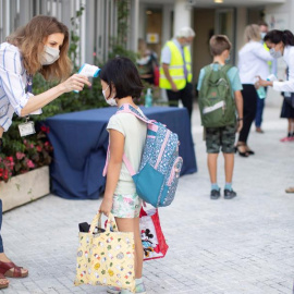 Una trabajadora toma la temperatura a una niña a la entrada del colegio privado internacional American School of Barcelona, situado en Esplugues de Llobregat (Barcelona) / EFE