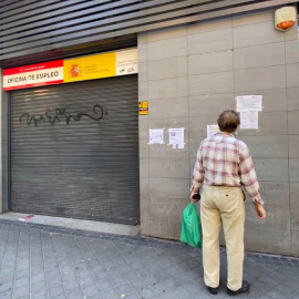 Una persona observa uno de los carteles con instrucciones para hacer trámites por internet colocados en la fachada de una oficina de empleo en Madrid. E.P./Eduardo Parra