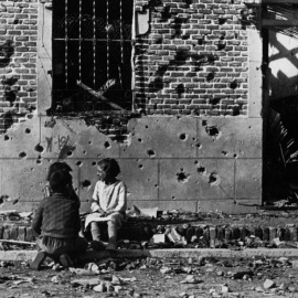 Robert Capa  Los niños juegan ajenos al horror de la guerra ante la fachada destrozada  por la metralla del número 10 de la calle Peironcely, November-December  1936  ©International Center of Photography/Magnum Photos