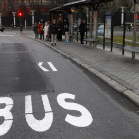 Varias personas esperando el autobús en el Paseo de la Castellana de Madrid. EFE
