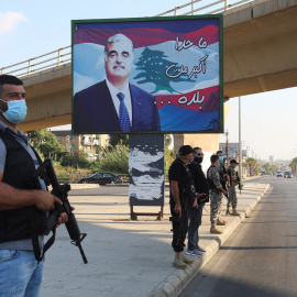 Miembros de las fuerzas de seguridad montan guardia en Sidón, al sur del Líbano, cerca de un cartel con la imagen del exprimer ministro libanés, Rafik al-Hariri, quien murió en un atentado suicida en 2005. REUTERS / Aziz Taher