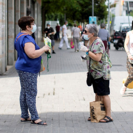 Dos mujeres mantienen la distancia social mientras hablan en una calle de Barcelona. - EFE
