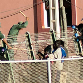 Agentes de la Guardia Civil y las fuerzas auxiliares marroquíes tratan de impedir que que varias personas migrantes salten la valla de Melilla.- CAMINANDO FRONTERAS