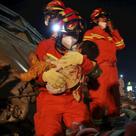 El servicio de rescate saca en brazos a un niño que había quedado sepultado por el derrumbe del centro de cuarentena en Quanzhou./ Xiao Fan (EFE/EPA/FEATURECHINA)