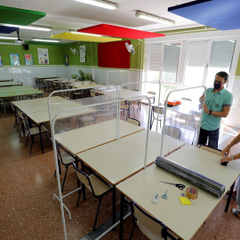 Xavi Leal y Carolina Ramos, director y jefa de estudios, respectivamente, del CEIP Jaume I de Catarroja, colocan los parabanes, realizados con unos percheros y una lámina de plástico transparente, para prepararse para la vuelta a las aulas en la Comunit